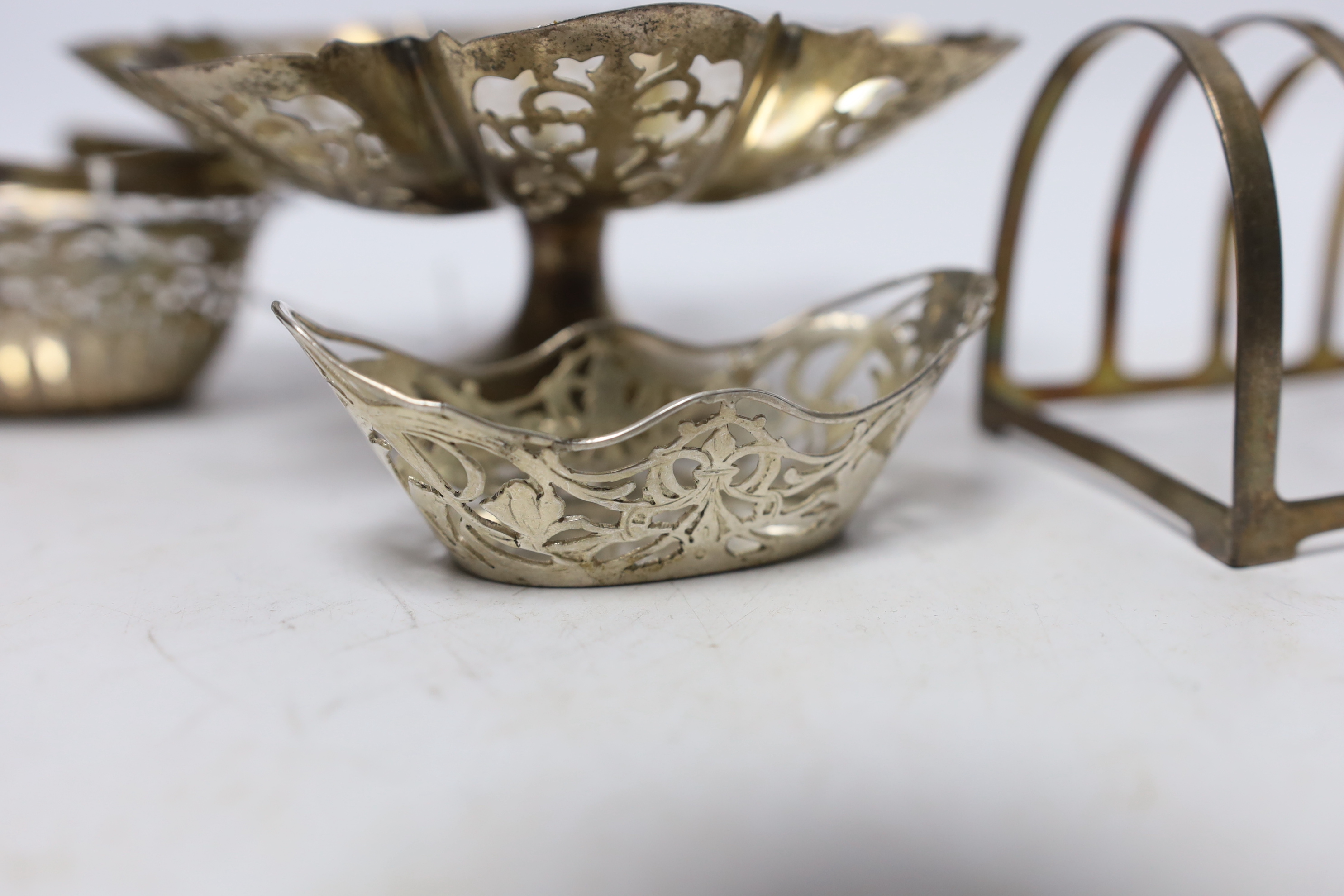 A small silver basket, a pierced silver pedestal dish, a George V silver five bar toast rack and a pierced silver bonbon dish, 10.2oz.